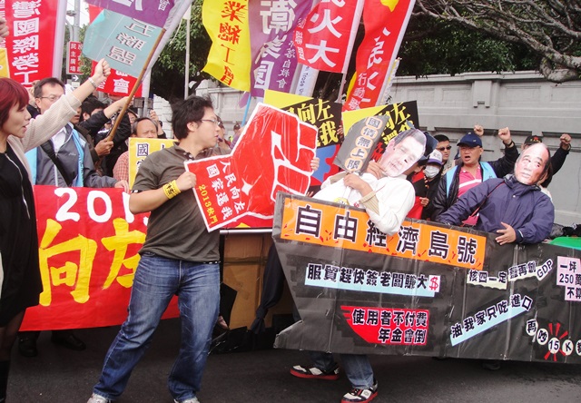 划著紙板做成的「自由經濟島號」，人民火大行動聯盟今（12）日上午為週日（17日）的秋鬥召開造勢記者會，表示要以一記「左勾拳」，將無法保障廣大人民的施政打回正軌。圖：王立柔/攝