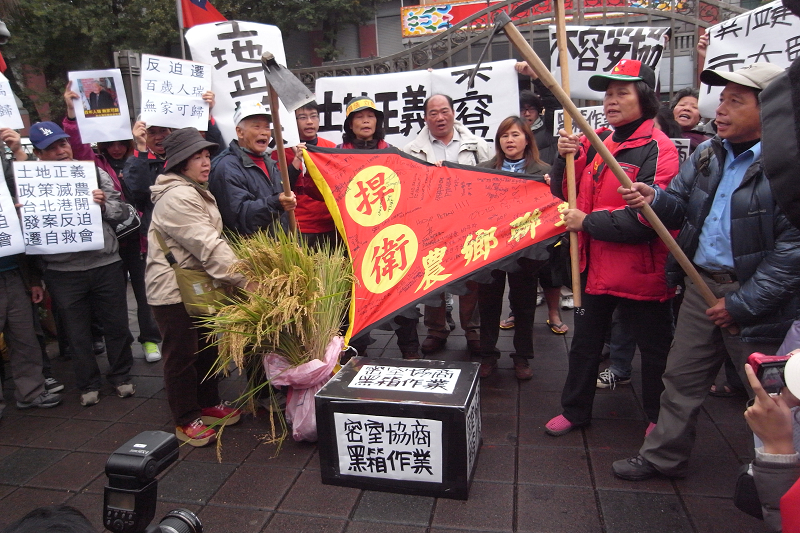 台灣農村陣線及全台遭不當徵收的農民12日上午在立法院前高呼「協商要透明、正義不打折」，他們並在現場用鋤頭打破「密室黑箱」，裡頭露出鈔票和選票，諷刺立委只顧才談不顧民意。圖片：楊宗興/攝