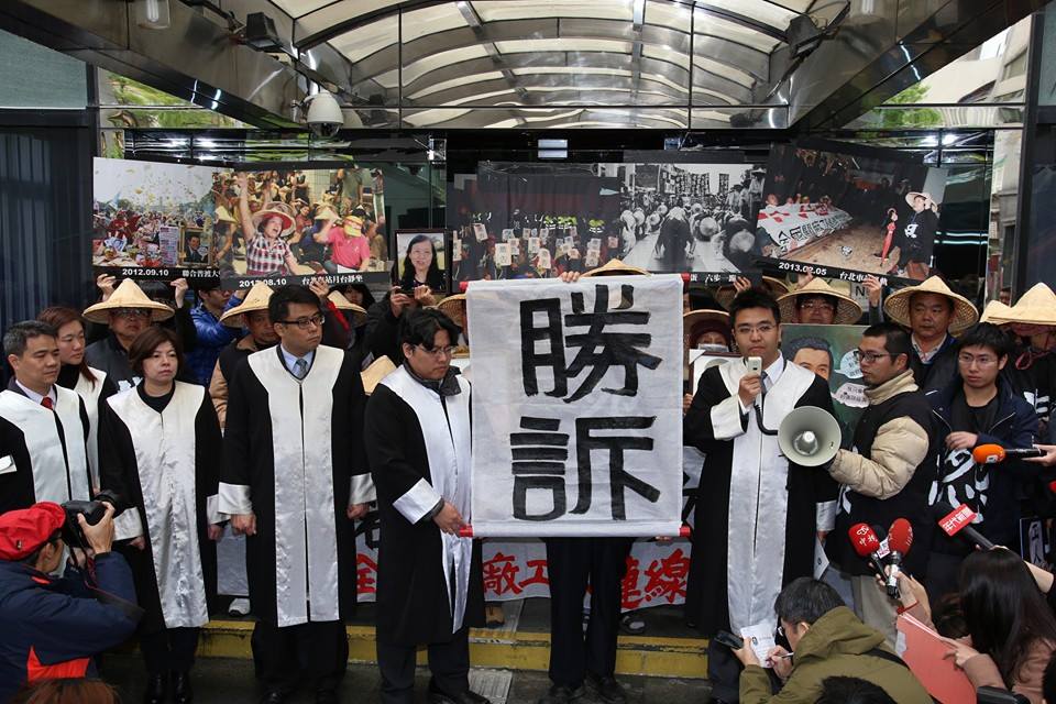 3月7日台北高等行政法院宣判後，關廠工人與律師在法院門口高舉勝訴的牌子。圖：新頭殼資料照片
