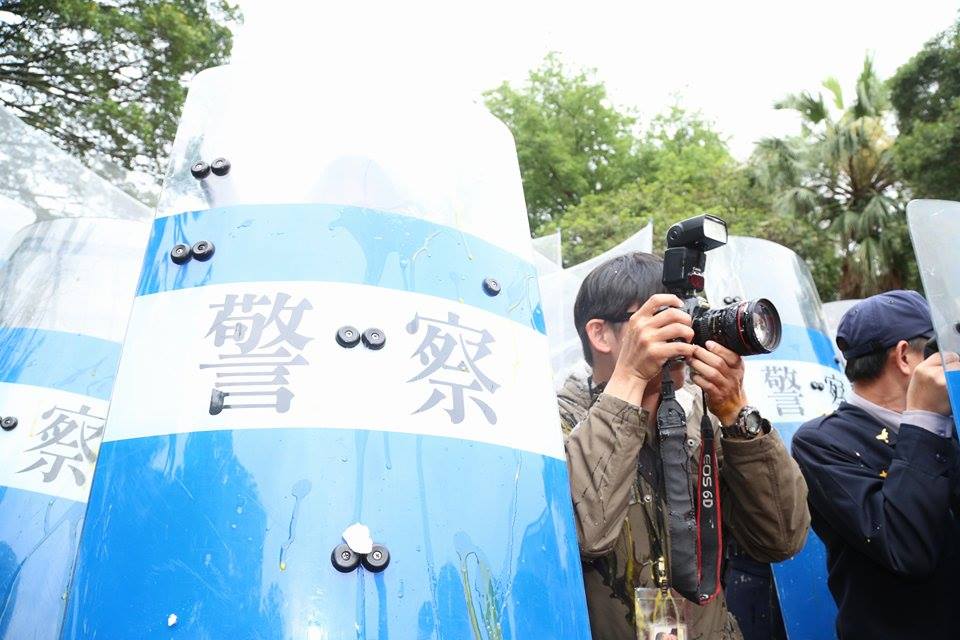 一位攝影記者在拍攝丟蛋過程，身上、相機都遭到蛋洗。圖：林雨佑/攝