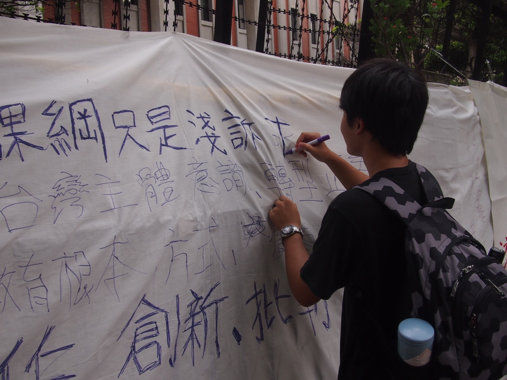 學生於拒馬處掛上長型帷幕，提供麥克筆，供民眾表達意見。圖:何星瑩/攝