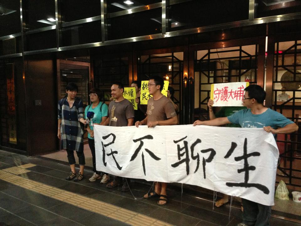 白米炸彈客楊儒門、李建誠19日潑漆後，在台北地檢署拉布條表達理念。圖：翻拍自臉書