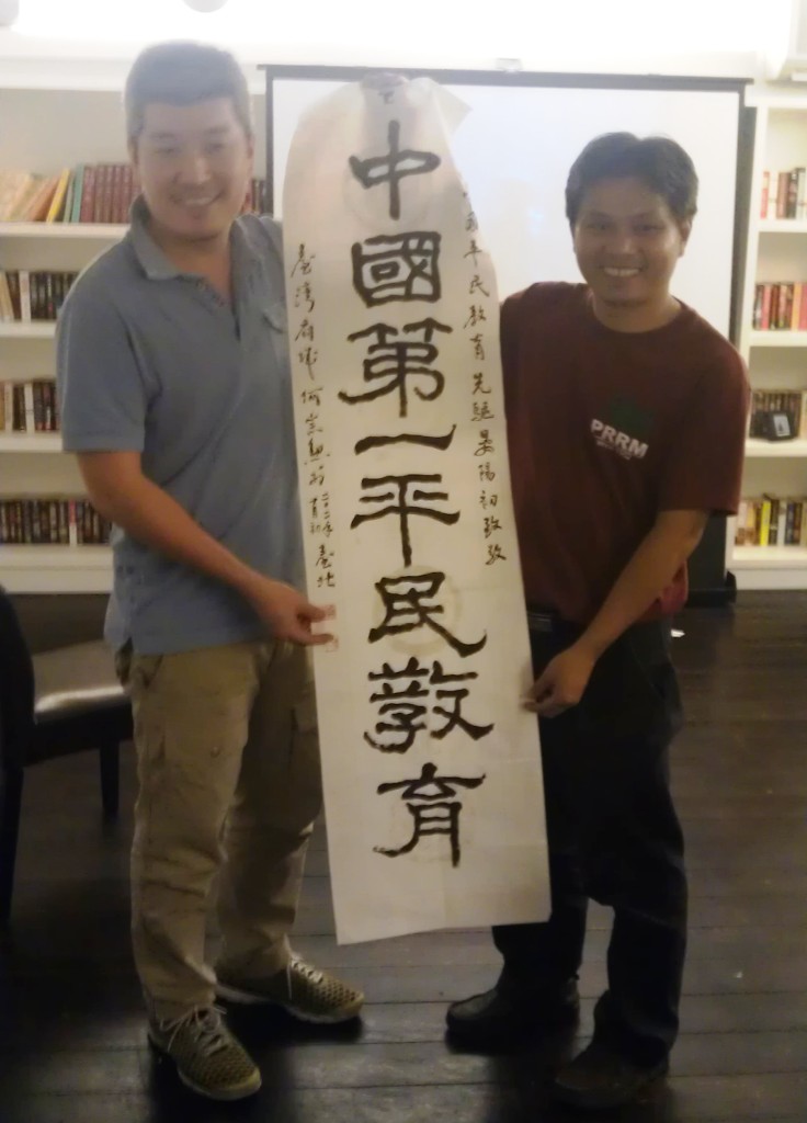 中國沙龍發起人何宗勳與邱建生合影，並贈上由他書寫的「中國第一平民教育」書法給邱建生。圖片來源:莊豐嘉攝影