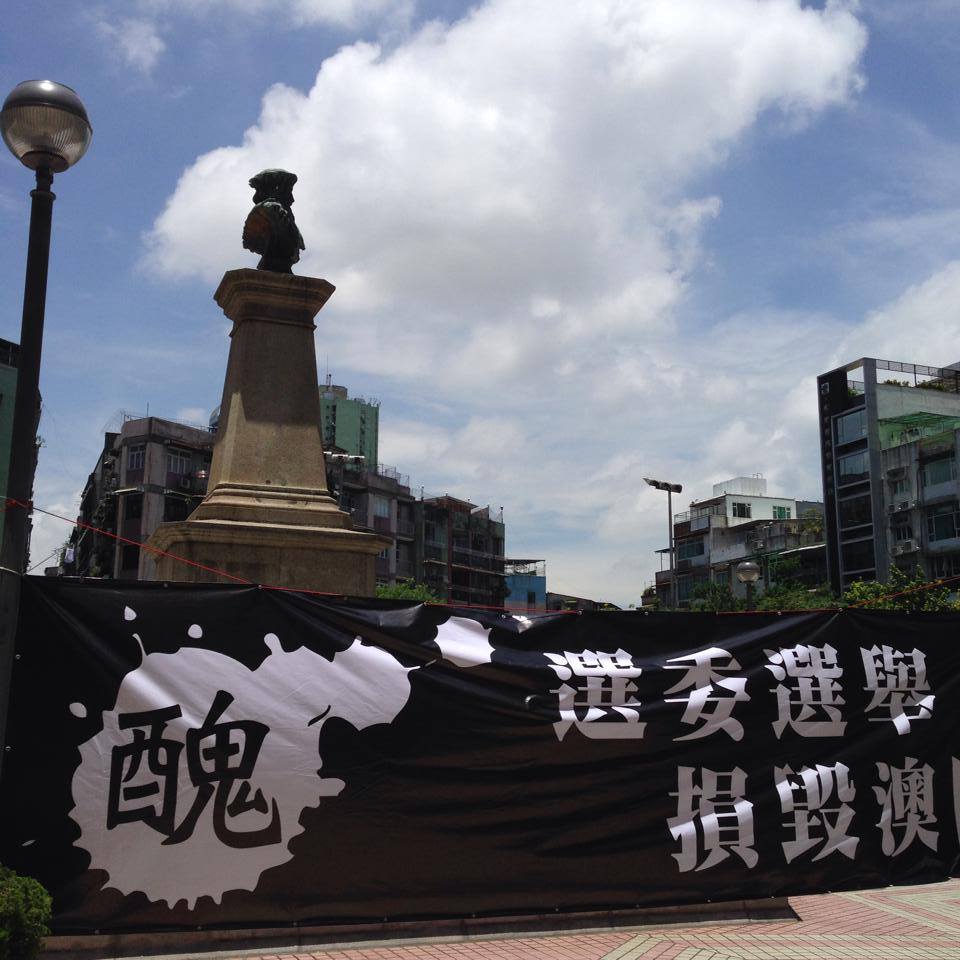 數個公民團體在澳門選委會委員選舉場合外，高舉標語諷刺選委選舉並非真正的民主。圖：翻攝自澳門良心臉書。
