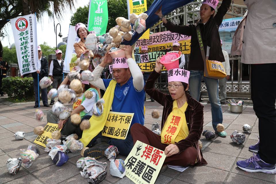 環團上演行動劇，把報紙球不停裝入藍色大布中，象徵廢土、垃圾不斷在水庫淤積，諷刺水庫淤積嚴重，還要修法開放開發，並把這些「淤積物」一傾而下。圖：林雨佑/攝