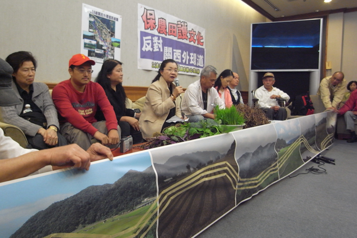 竹縣居民在現場拉開一幅橫幅的關西稻田景色，但上頭用膠帶貼出關西外環道的預定路線，硬生生將田園美景切割。圖：楊宗興/攝