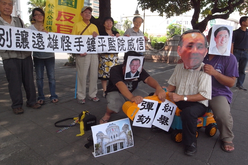 松菸公園催生聯盟在監院門口表演行動劇，內容是遠雄集團創辦人趙藤雄及台北市長郝龍斌，兩人共乘一台怪手要將監察院輾平，但院長王建煊手拿「彈劾」、「糾舉」阻止怪手，象徵要王院長出面阻止大巨蛋違法損及監院威信。圖片：楊宗興/攝