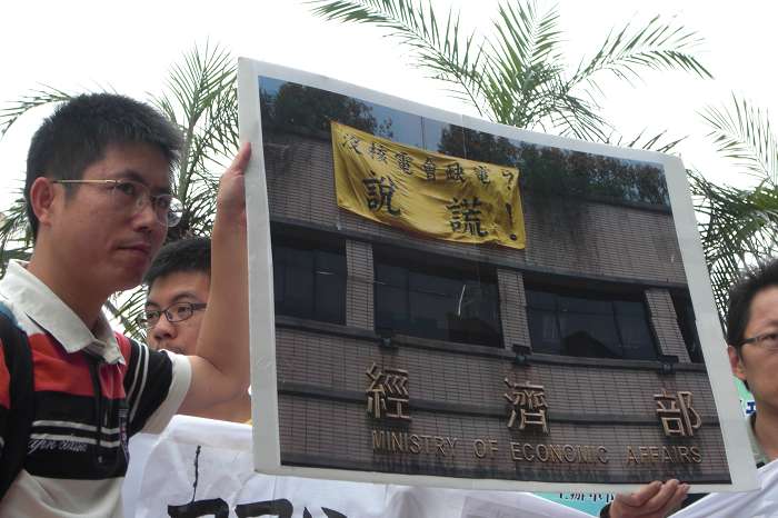 民間團體拿出之前懸掛在經濟部上「說謊」旗幟的照片，再度指控政府用「缺電」恐嚇人民的謊言。圖片：黃沛云/攝