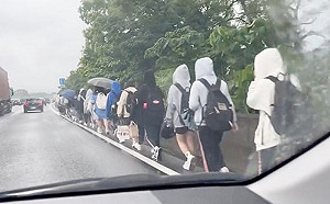 國道驚見「學生排隊淋雨走路」！30多人背書包走路肩 真相曝光