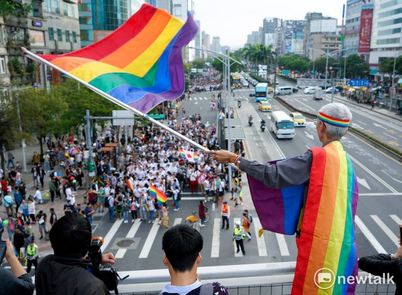 剛剛獲得今年的總統文化獎的婚姻平權志工祁家威，在同志遊行行進路線中，站在高點揮舞彩虹旗，為參與遊行的同志們加油打氣。   圖：張良一/攝