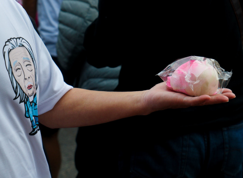 小英志工會成員在現場發放豬腳麵線和壽桃，分享史明一百歲生日的喜悅。   圖：張良一/攝