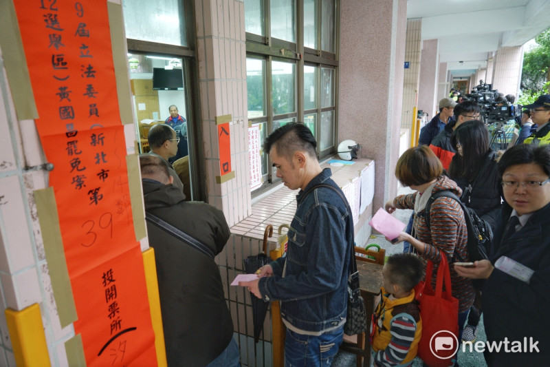 台灣民主政治頭一遭的黃國昌罷免案今舉行，由於氣溫驟降又下雨，投票並不踴躍，圖為民眾在投票所外等待投票。   圖：張良一/攝