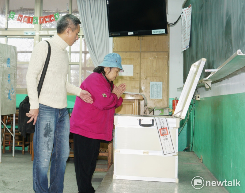 台灣民主政治史上頭一遭的黃國昌罷免案今投票，支持罷免黃國昌的孫繼正帶著母親去投票，而她的母親在投完票後，對著投票櫃雙手合十祈禱。   圖：張良一/攝