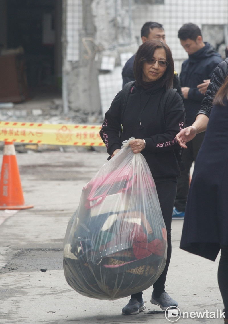 一位住在花蓮國盛六街的災民，扛著用大型塑膠袋裝著的衣服細軟，神情凝重的開車地震重創的房子。   圖：張良一/攝