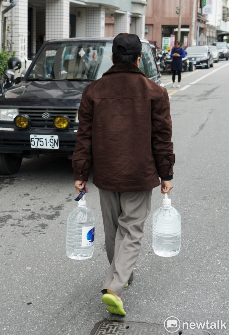 地震過後，許多地區仍未供水，一位無水可用的民眾自行提水回家。   圖：張良一/攝
