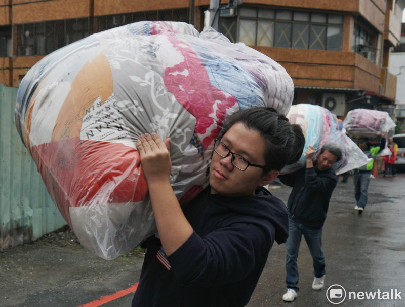 三位志工將民眾捐贈棉被搬去給災民使用。   圖：張良一/攝