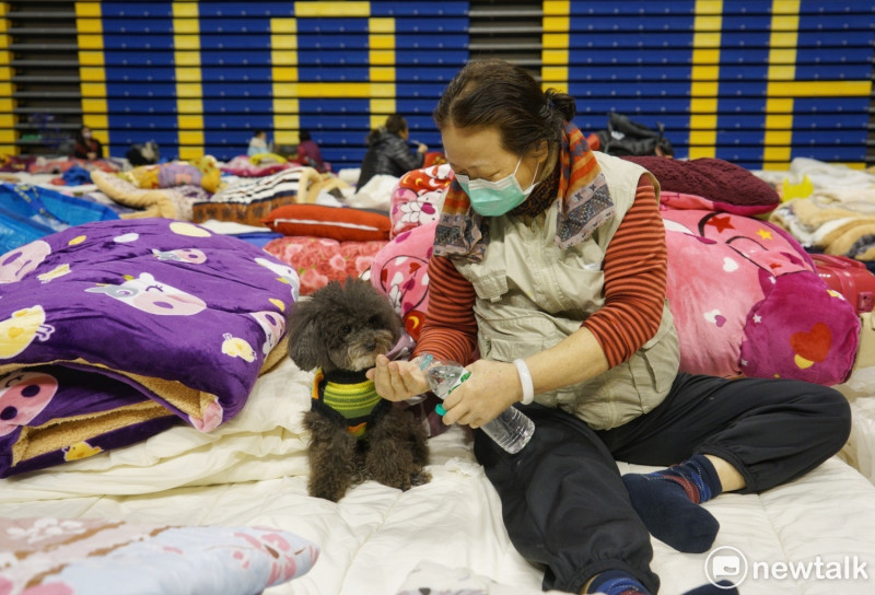 一位劫後餘生的災民在花蓮小巨蛋收容中心避難時，倒水給她的愛犬喝。   圖：張良一/攝