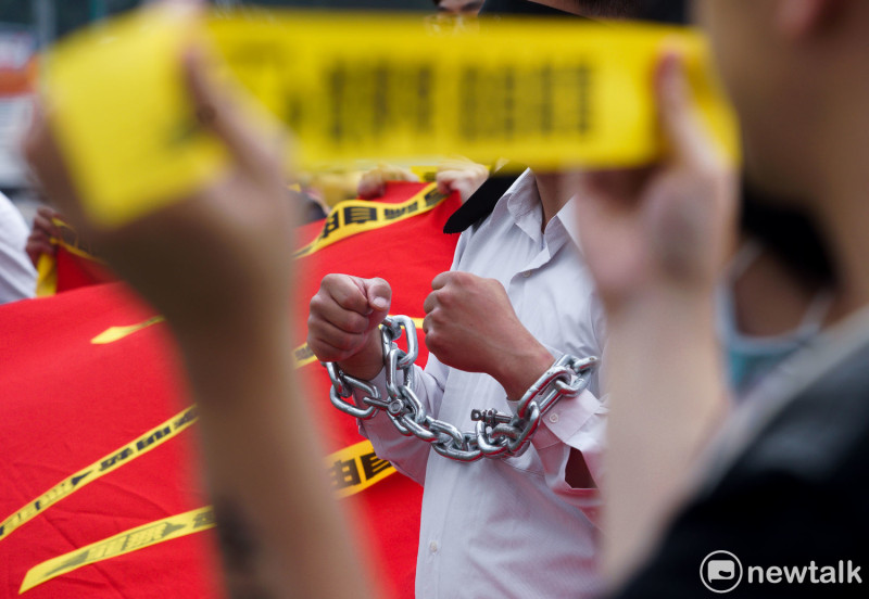 今天是李明哲被中國逮捕一週年，李明哲救援大隊在總統府前舉行記者會，透過手銬、黑布蒙臉以及象徵中國極權的紅色大布條，控訴李明哲被中國限制人身自由，更凸顯台灣的民主與人權受到極大的傷害。   圖：張良一 /攝