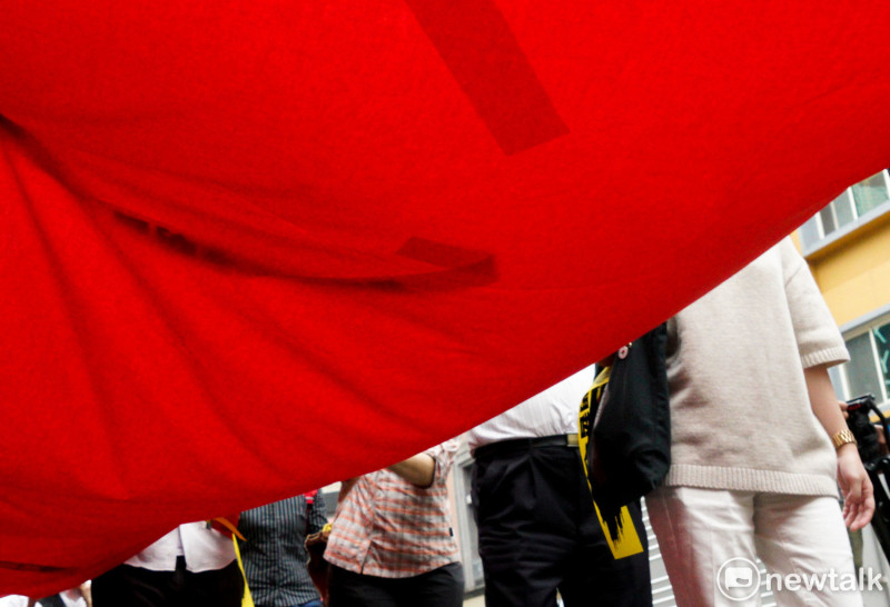 聲援李明哲的NGO 團體拉著一條象徵中國極權的大紅布在台北街頭遊行，象徵著對台灣民主與人權的威脅。他們希望大家一起加入抗議中國極權的行動。   圖：張良一 /攝