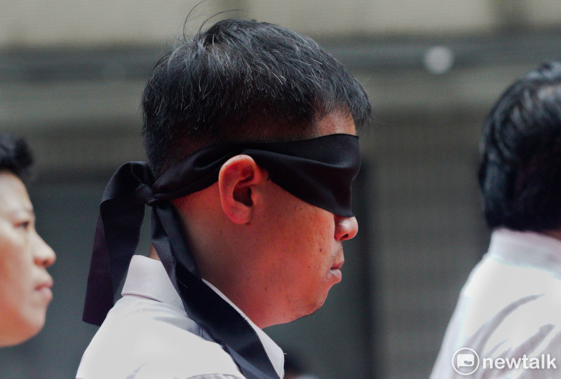 李明哲救援大隊的一位志工被黑布矇住眼睛，用來呈現李明哲被中國逮捕拘禁的視覺意象，同時也暗喻著人人都有可能變成下一個李明哲。   圖：張良一 /攝