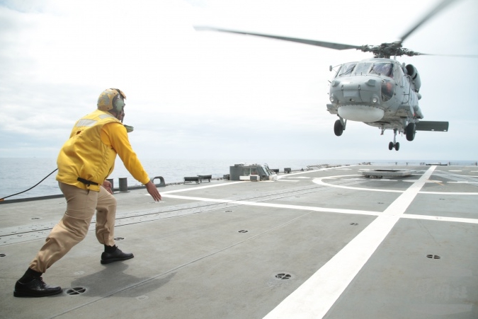 「直升機落艦」，過程中飛行員必須在空中準確判斷直升機與艦艇的距離、高度及速度落差，並隨時注意因海浪影響飛行甲板的水平變化，並藉由安全管制官的手勢，才能順利降落，難度相當高。   圖：軍聞社/提供