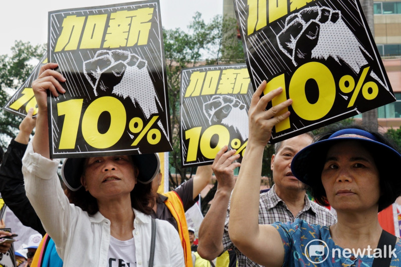 五一勞動節參與遊行的民眾高舉「加薪10%」紙牌表達訴求。   圖：張良一/攝