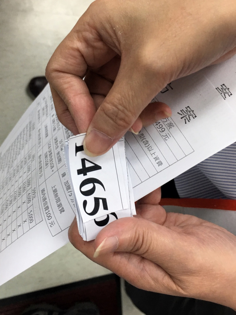 台北萬華的一處中華電信營業所，一位工作人員手上的號碼牌顯示連續兩天已有1400多位民眾申辦499吃到飽專案。   圖：張良一/攝