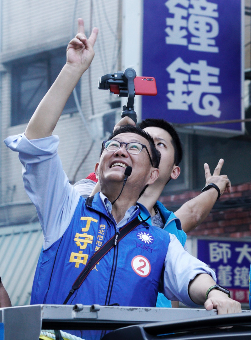國民黨台北市長候選人丁守中上午在中正、萬華區掃街時，向樓上住戶比出二號手勢。   圖：張良一/攝