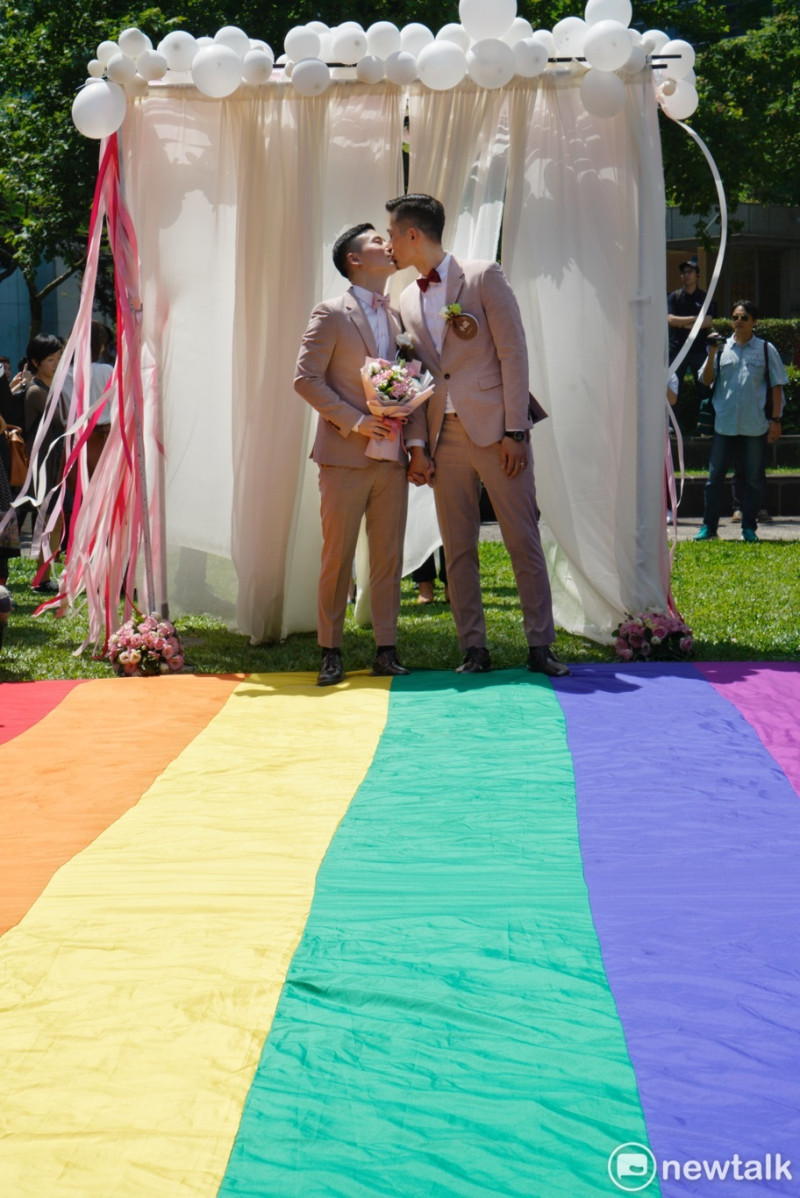 一對同性伴侶在信義區戶政事務所完成結婚登記後，在彩虹地壇上接吻。   圖：張良一/攝