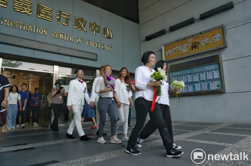 多對同性伴侶在台北市信義區戶政事務所辦完結婚登記後，一起步出信義行政中心。   圖：張良一/攝
