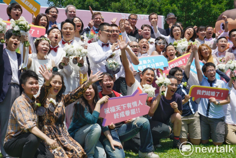 20對同性伴侶在台北市信義區戶政事務所完成結婚登記後，開心地在信義行政中心外合影。   圖：張良一/攝
