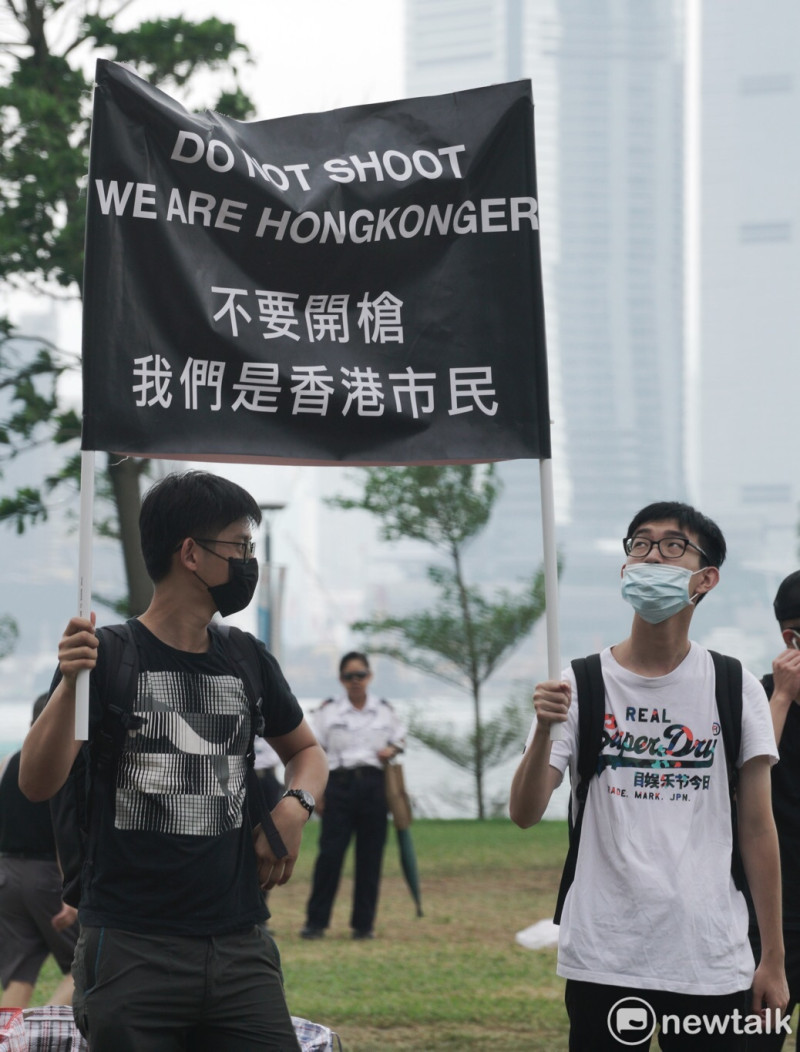 香港反送中示威青年高舉標牌，以「不要開槍 我們是香港市民」等字抗議港警對學生開槍。   圖：張良一/攝