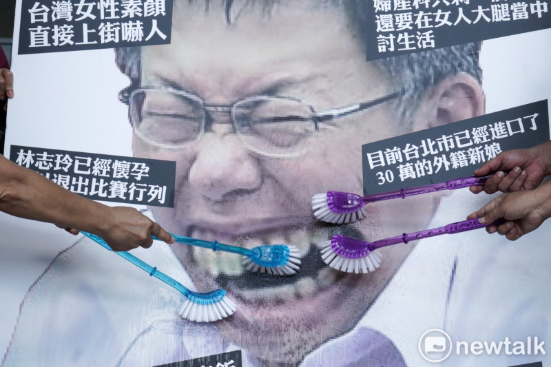 台灣團結聯盟成員在台北市政府前舉行的「請柯文哲管好市政、管好嘴巴」記者會中，用刷子刷柯文哲圖像中牙齒，藉此抗議柯文哲物化女性的諸多言論。   圖：張良一 / 攝