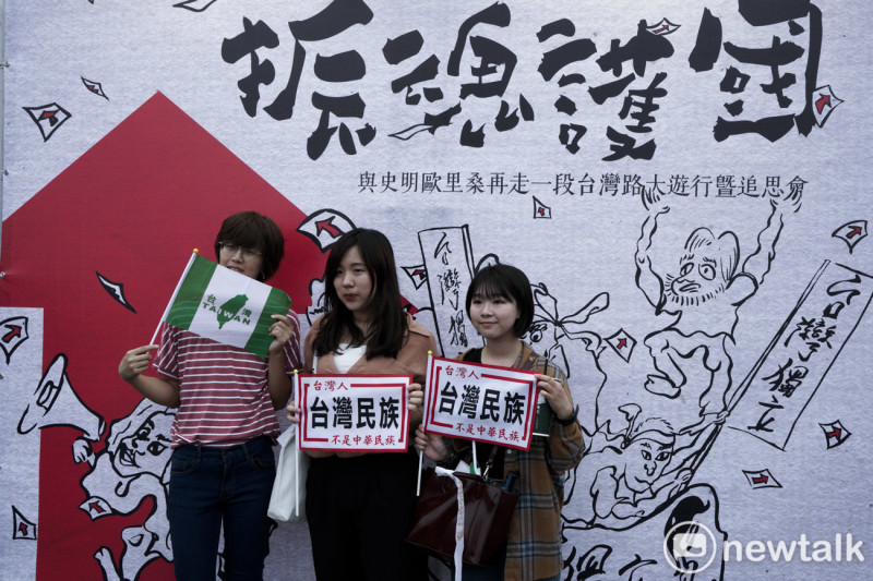 三位民眾拿著『台灣民族不是中華民族』的旗子在史明追思會看板前合影。   圖：張良一/攝