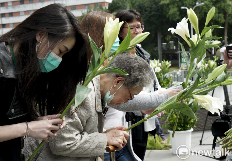 二二八受難者家屬向二二八受難者英靈獻上白色百合花致敬。   圖：張良一/攝