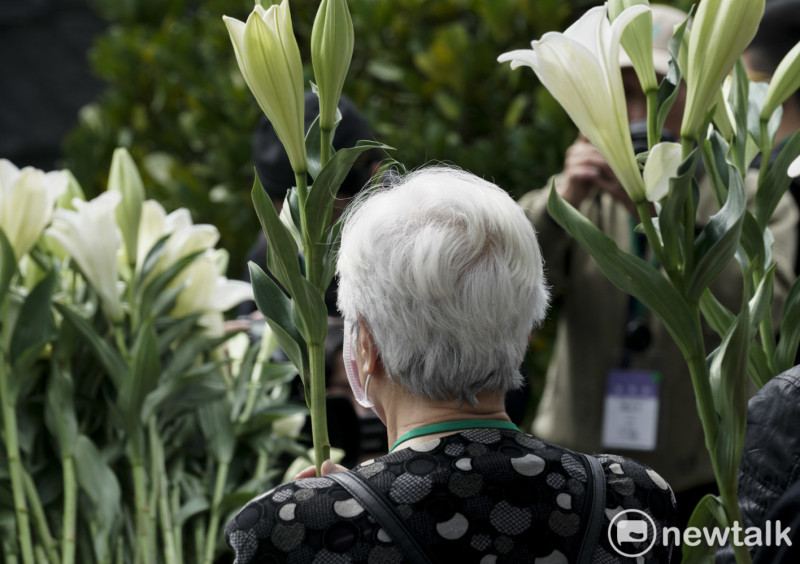 一位頭髮已白的二二八受難者家屬向二二八受難者英靈獻上白色百合花致敬。   圖：張良一/攝