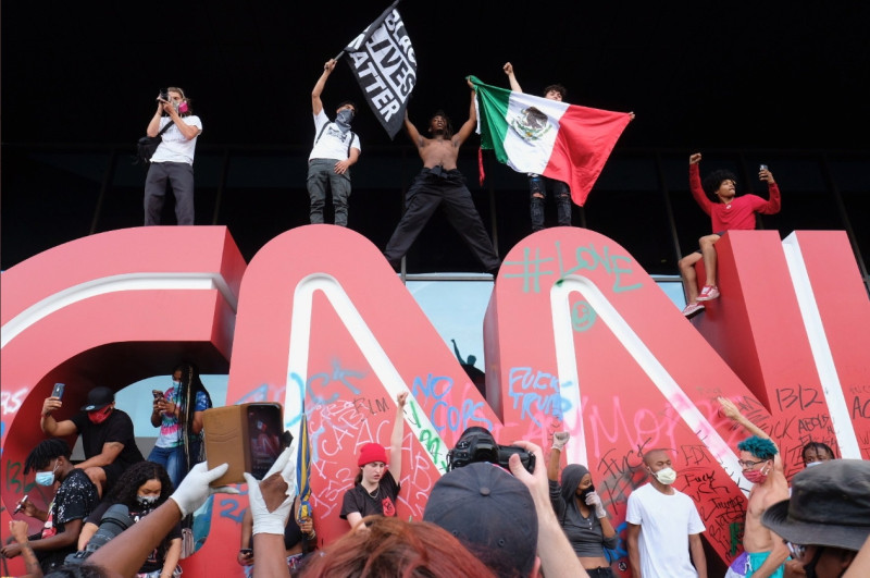 示威民眾站在「CNN」招牌上，斗大的招牌已被人噴漆、塗鴉。 圖：翻攝自推特