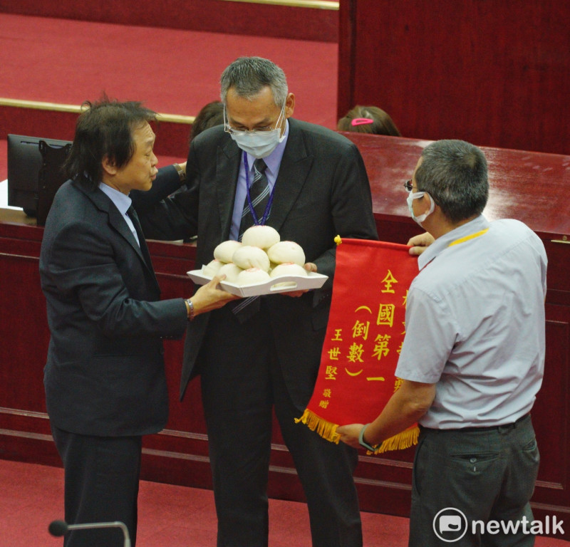 民進黨台北市議員王世堅送饅頭和倒數第一錦旗給台北市長柯文哲。   圖：張良一/ 攝