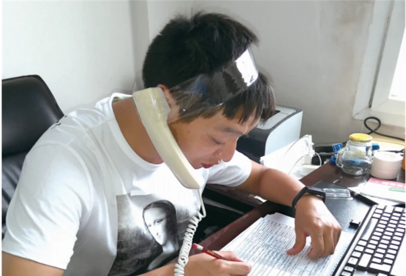 近日中國網路流傳一張圖片，一名男子用膠帶把電話聽筒綁在頭上，只是為了通知更多市民接種第二劑新冠疫苗。   圖：翻攝自騰訊網
