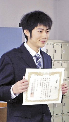  2012 年春天，位於大阪市的日本語言學校畢業典禮上，王建彬穿著西裝自信地拿著獎狀。 圖／取自Facebook 