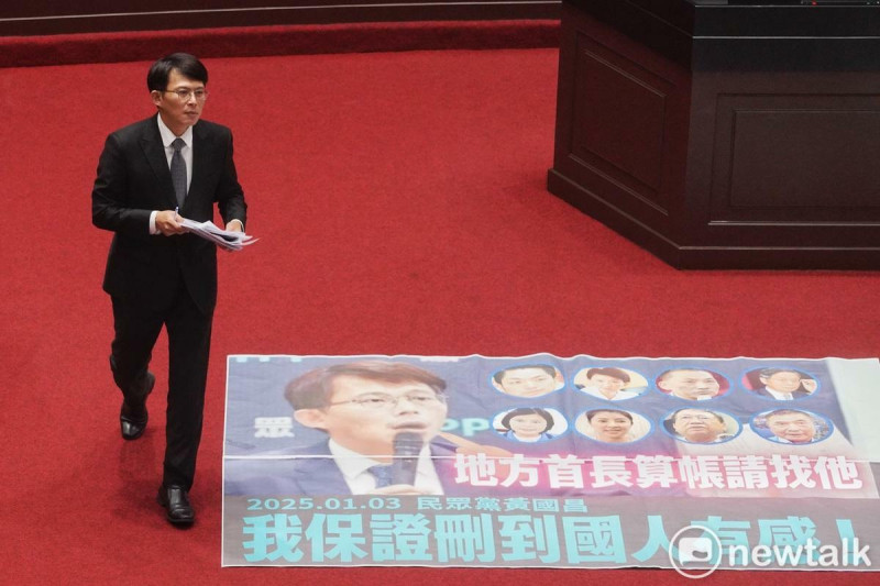 台灣民眾黨裡院黨團總召黃國昌在立院院會抨擊行政院刪除對地方補助款，民進黨團則在議場內張貼黃國昌「我保證刪到人民有感！」牌子。   圖：張良一 / 攝