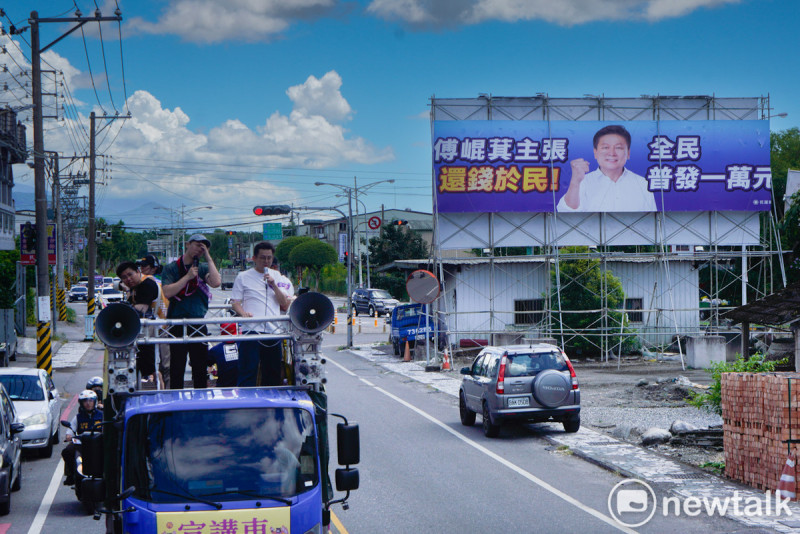 護國大遶境掃街車隊進入鳳林市區前,經過國民黨立委傅崐萁製作的「全民普發一萬元」的大型廣告。 圖:張良一/攝