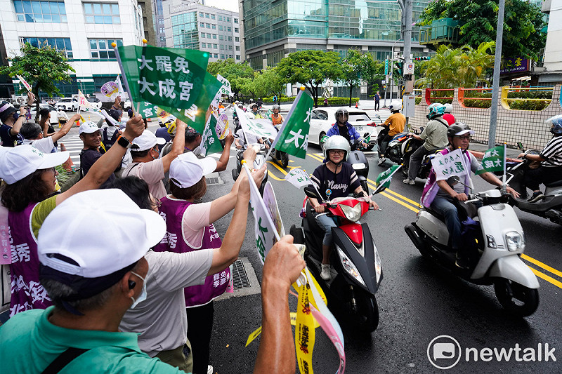 護國大遶境掃街車隊抵達，民眾手持「大罷免大成宮」旗幟呼應。   圖：張良一/攝