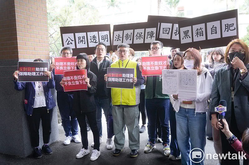 針對國民黨立委陳玉珍提案修修法「助理費除罪化」，立委院國會助理在立院大門口拉開白布條並高舉手舉牌呼喊口號，要求陳玉珍撤案。圖為陳玉珍到場和助理溝通時助理高舉手舉牌回應。   圖：張良一/攝