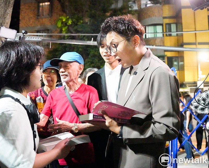  民進黨台北市長參選人沈伯洋出席「台北．無限之城」論壇前，一位學生拿著沈伯洋的著作請他簽名時，沈伯洋露出驚訝的表情。 圖：張良一/攝 