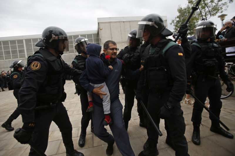 一民抱著小孩的男子欲前往加泰隆尼亞獨立公投投票所時，遭到警方強制驅離。   圖 : 達志影像/ 美聯社