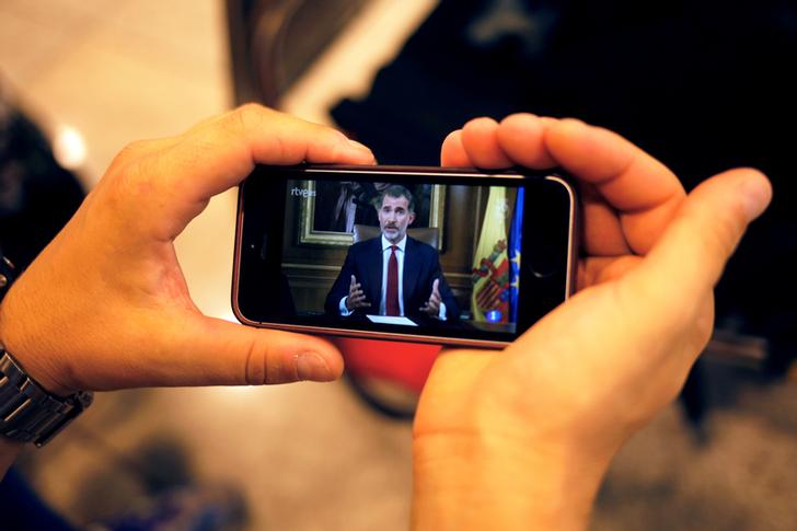 西班牙的一名民眾，以手機收看國王演說。   圖：達志影像／路透社