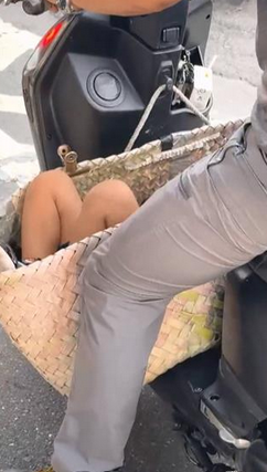 高雄一名老翁違規將孩童置於機車腳踏板上的菜籃裡，嚇壞目擊民眾。   圖：翻攝自網路