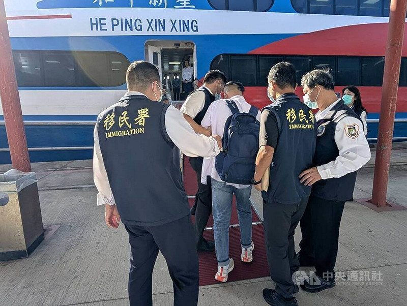 盧姓中國籍男子（背後背包者）6日到金門縣政府前拋撒寫有「統一台灣」等字句傳單，移民署南區事務大隊金門專勤隊調查後，認為盧男從事與許可來台目的不符活動，下午將人強制驅逐出境。中央社記者吳玟嶸攝　114年11月6日   