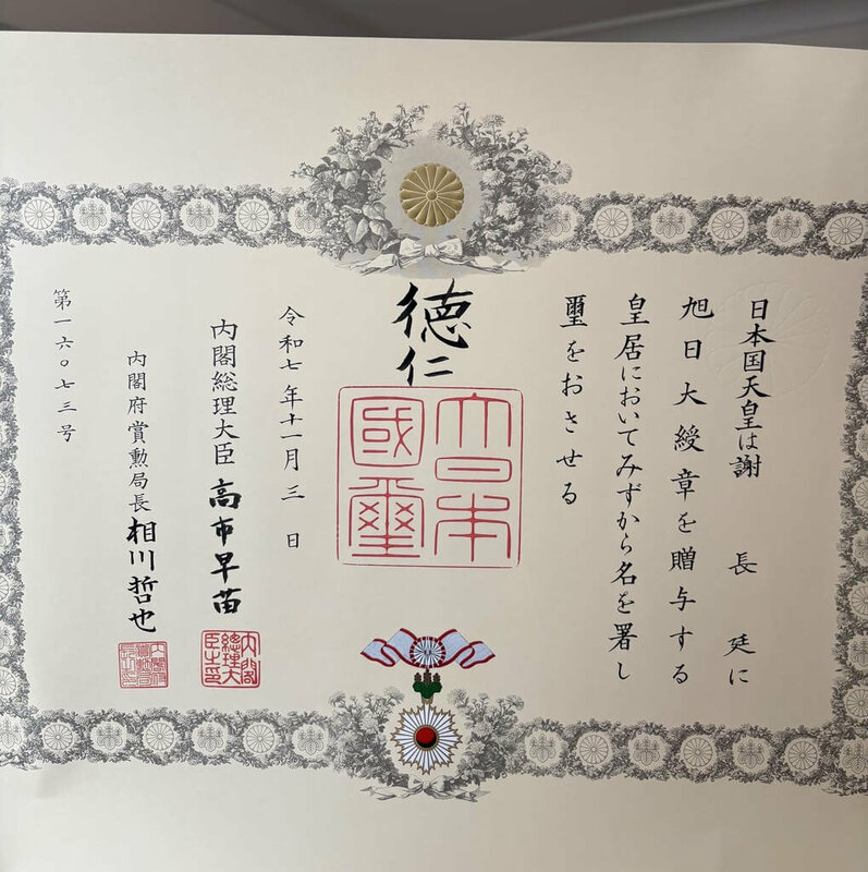 日本秋季授勳的大綬章親授式11日於皇居舉行，日皇德仁在皇居「松之間」親自授勳，日本首相高市早苗遞交勳記（授予勳章的證明文件）。總統府資政、前駐日代表謝長廷獲授「旭日大綬章」。   圖：謝長廷提供